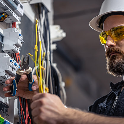 male-electrician-works-switchboard-with-electrical-connecting-cable